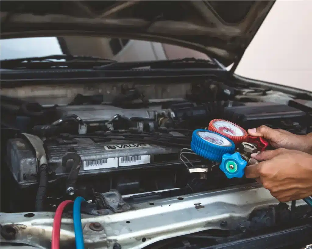 Auto air conditioning and heating services in Wake Forest with Pleasant Automotive, NC. A person holding a pressure gauge to check the engine of a car