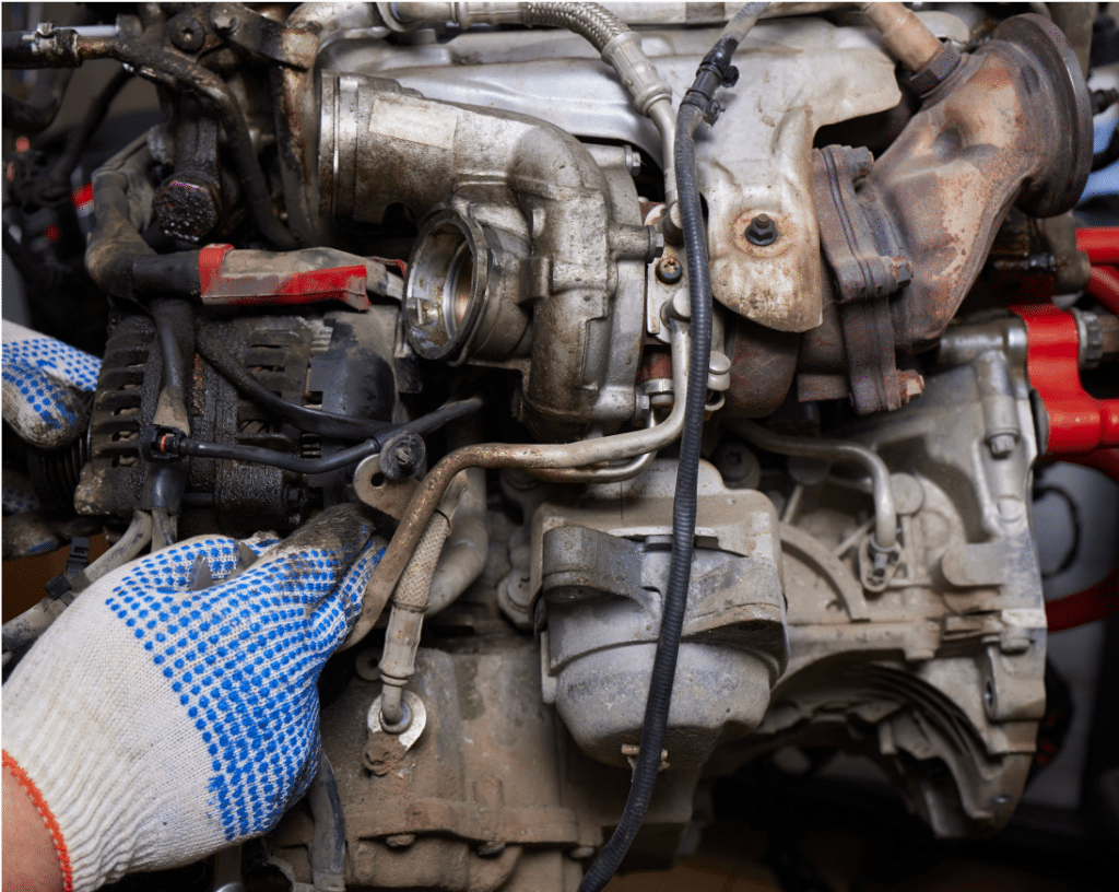 Engine repair and diagnostics services in Wake Forest, NC at Pleasant Automotive . A hand holding a gloved hand over a dirty engine