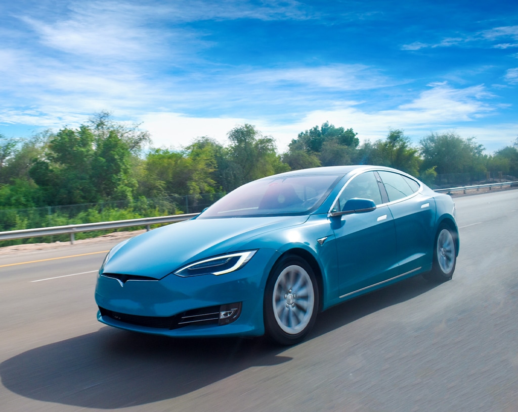 Tesla repair & maintenance, ev repair in Wake Forest and Raleigh, NC with Pleasant Automotive. Image of blue electric vehicle driving on a road during a sunny day.