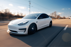 tesla spring maintenance, Auto Repair Services in Wake Forest, NC at Pleasant Automotive. White Tesla Model 3 with black wheels driving on a highway under a clear blue sky.