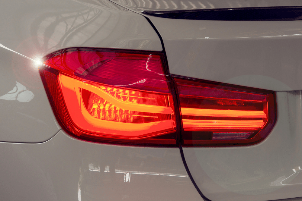 brake warning light, Auto Repair Services in Wake Forest, NC at Pleasant Automotive. Close-up of a modern red LED tail light illuminated on a white vehicle, showing sleek and angular design lines.