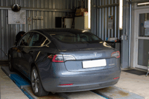 Tesla Maintenance Schedule in Wake Forest, NC by Pleasant Automotive. Tesla Model 3 in a service garage undergoing maintenance inspection, representing trusted Tesla care and service.
