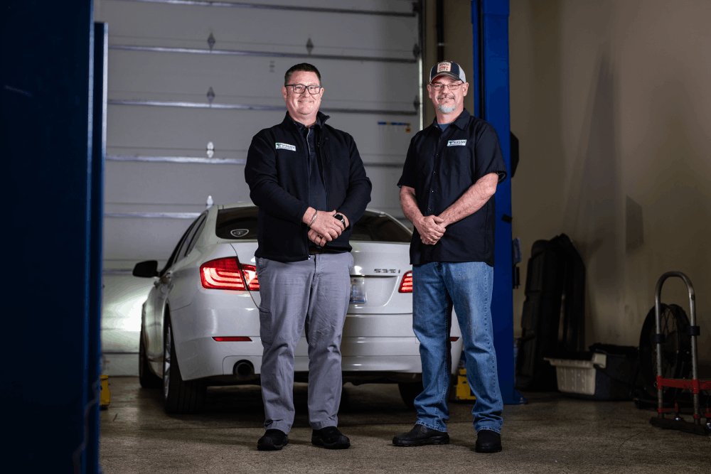 Auto repair in Wake Forest, NC by Pleasant Automotive. Image of two professional technicians standing in the shop bay in front of a vehicle on a lift, highlighting trusted, team-based service and dependable vehicle care.