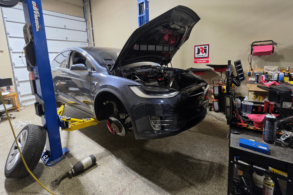 Car maintenance, auto repair in Wake Forest, NC at Pleasant Automotive. Image of a Tesla Model X on a lift receiving professional maintenance and repair by experienced technicians.